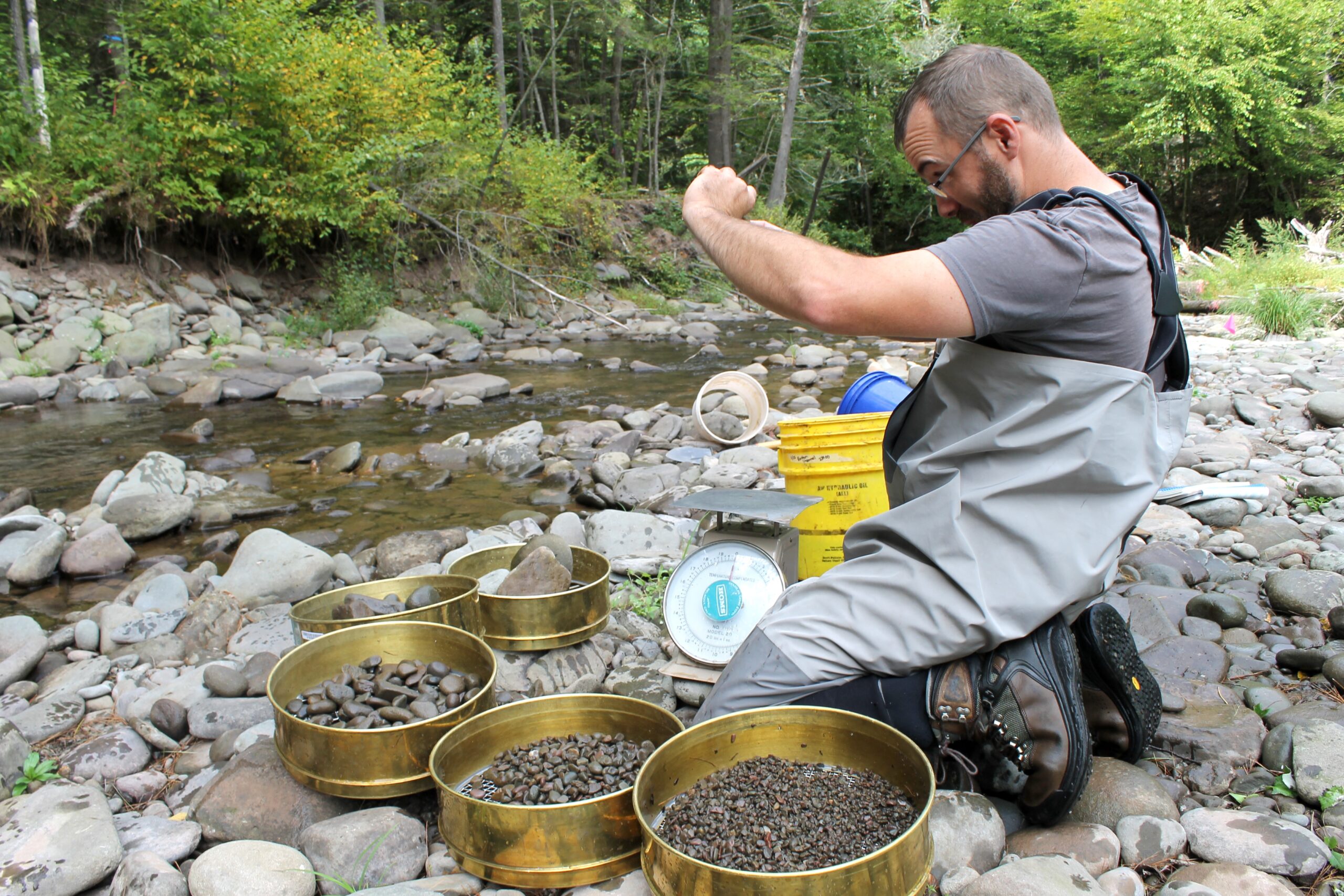 Program staff member measuring cobble next to a stream